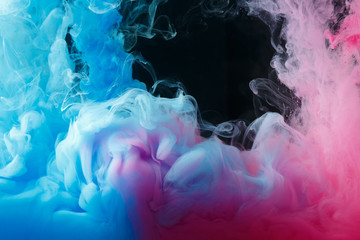 A cloud of colored acrylic paint in water. A drop of colorful ink dissolves in water on a black background. Abstract background.