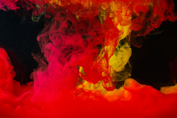 A cloud of colored acrylic paint in water. A drop of colorful ink dissolves in water on a black background. Abstract background.