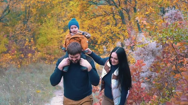 Slow Motion Happy Family: Father, Mother And Child Walking In Autumn Park