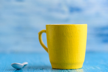 Yellow mug on a wooden background photographed close-up.