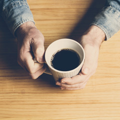 Mano de hombre sosteniendo una deliciosa taza de café sobre un fondo de madera rústica. Vista...