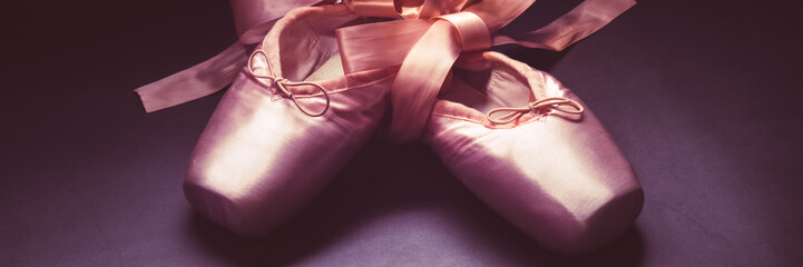 Pointe shoes ballet dance shoes with a bow of ribbons beautifully folded on a dark background.