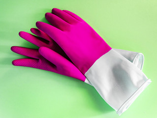 Closeup top view of beautiful pink latex gloves on green background. housework concept. General or regular cleanup. Commercial cleaning company. household and cleaning gloves