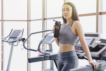 Fototapeta premium Girl in the gym are trained on treadmill and drink water