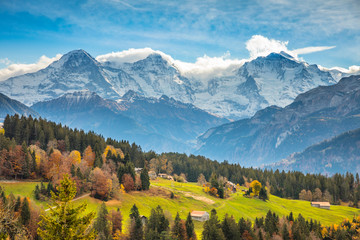 Scenic view of grassy landscape with snowcapped mountains against cloudy sky