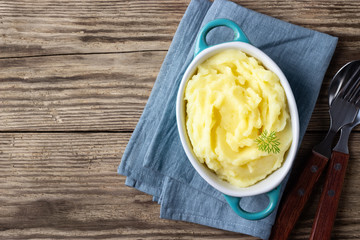 Mashed potatoes in bowl on wooden rustic background. Top view. Copy space.