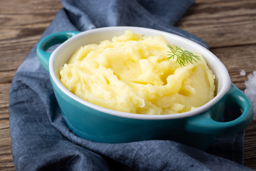 Mashed potatoes in bowl on wooden table.