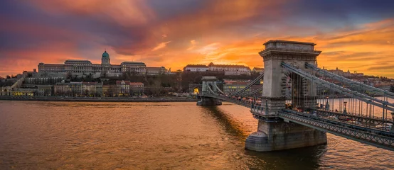 Wandaufkleber Budapest, Ungarn - Panoramablick auf die Szechenyi-Kettenbrücke mit dem Buda-Tunnel und dem Königspalast von Buda im Hintergrund mit einem dramatischen, farbenfrohen Sonnenuntergang © zgphotography