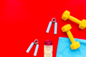 workout with bars, bottle of water and wrist builder red background top view mockup