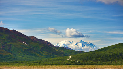 Obraz premium With its huge mountains and surrounded by a wonderful biodiversity lies the Denali National Park and Preserve. Touristic route and cloud sky. Landscape, fine art. Parks Hwy, Alaska, EUA: July 28, 2018