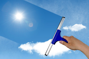 squeegee cleaning a dirty window, spring cleaning concept, blue sky with copy space