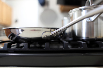 Modern gas stove with stainless steel cookware in a home kitchen.