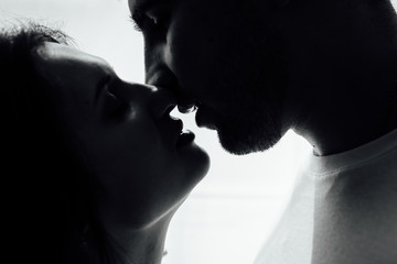 Couple kissing near window. Man and woman in darkness. Sweet taste of your lips