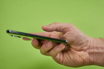                   hand holds an iphone x in front of green background
