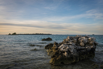 Large dead corals appear because of low tide on Harapan Island, Indonesia with a colorful morning sky