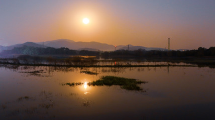 The Full moon rising from behind the hills with the lake in the foreground, Goa, India.