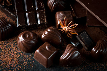 Assortment of dark, white and milk chocolate stack, chips. Chocolate and coffee beans on rustic wooden sacking background. Spices, cinnamon. Selective macro focus. Chocolates background. Sweets