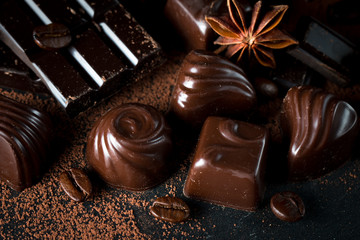 Assortment of dark, white and milk chocolate stack, chips. Chocolate and coffee beans on rustic wooden sacking background. Spices, cinnamon. Selective macro focus. Chocolates background. Sweets