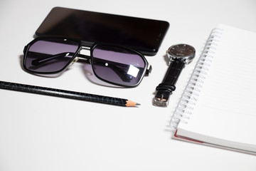 Flat lay smart phone notebook and pen sunglasses watch