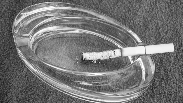 Time Lapse. A cigarette burns in an ashtray. Black and white video. 4k.