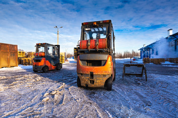 Forklift loaders for warehouse are waiting work outdoors during frosty day in the cargo center....