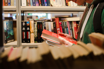 młody mężczyzna wybiera książkę w bibliotece
