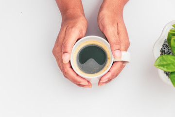 girl's hands holding coffee cup with plant flat lay top view