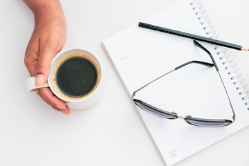 Woman hand holding cup of coffee open notebook Flat lay