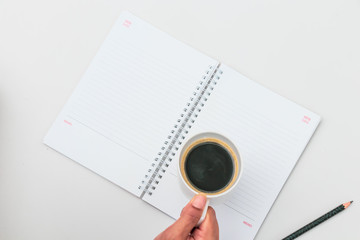 Woman hand holding cup of coffee open notebook Flat lay