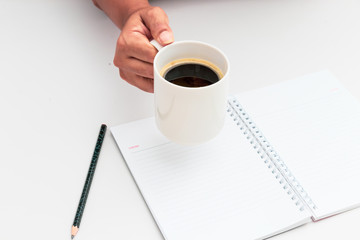 Woman hand holding cup of coffee open notebook Flat lay
