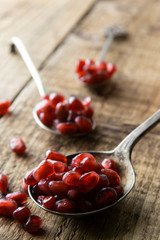 Pomegranate seeds in spoon on rustic wooden background. Detox, diet, fruits ingredient, cooking healthy food or dessert. Copy space