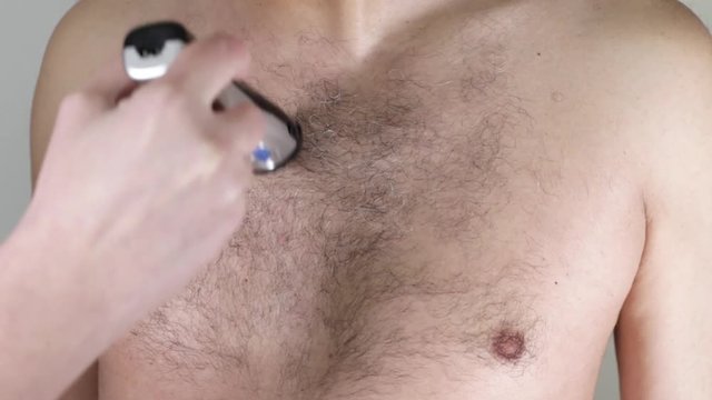 closeup of a caucasian man trimming the hair of his body with an electric trimmer