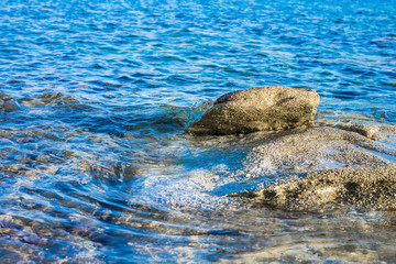 vivid blue shallow water natural reservoir near rocky shoreline with underwater stone outdoor beautiful background wallpaper pattern, copy space for text