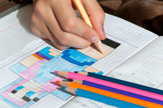 Child hand draws the multicolored minecraft picture.