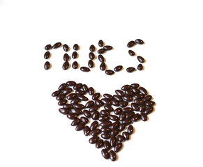Nuts arranged in heart shape on background. Food image close up candy, chocolate milk, extra dark almond nuts. Love Texture on white grey table top view