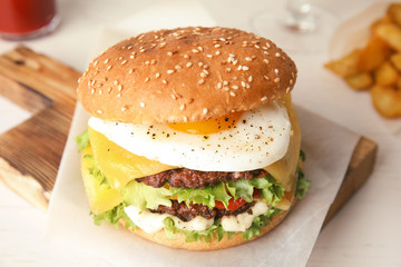 Tasty burger with fried egg on wooden board