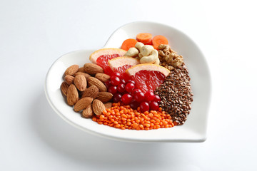 Plate with products for heart-healthy diet on white background