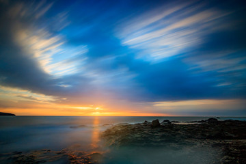 Fototapeta na wymiar blue picture look of a sunrise on Fuerteventura Canarias in Spain. beautiful sea view, with rocks and soft clouds and water. great sunlight