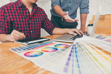 Fototapeta premium Teamwork of young creative designers working on project together and choose color swatch samples for selection coloring on digital graphic tablet at workspace