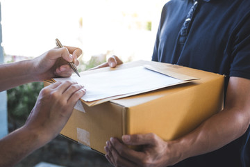 Delivery mail man giving parcel box to recipient and signature form, Young owner signing receipt of delivery package from post shipment courier, Home delivery service and working with service mind