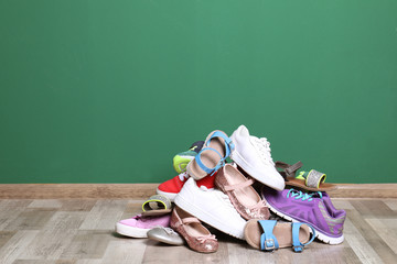 Heap of different shoes on floor against color wall. Space for text