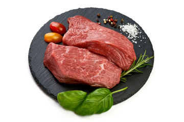 Fresh raw beef steak with spices on a slate shale plate, sliced meat, close-up, isolated on white background