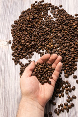 Coffee beans in hands on wooden background