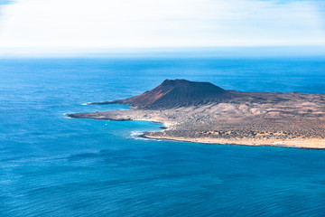 Unique panoramic magnificent aerial view of volcano cone at volcanic island La Graciosa south coast, in Atlantic ocean, from Mirador del Rio, Lanzarote, Canary Islands, Spain. Travel concept.