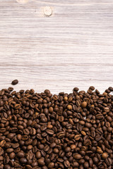 Roasted coffee beans in bulk on a light wooden background. dark cofee roasted grain flavor aroma cafe, natural coffe shop background, top view from above, copy space