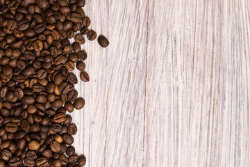 Roasted coffee beans in bulk on a light wooden background. dark cofee roasted grain flavor aroma cafe, natural coffe shop background, top view from above, copy space