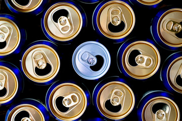 Abstract pattern of opened aluminium cans, top view. One white soda or beer can standing out among yellow and blue cans. Excess drinking, consumerism, alcoholism, or 'be different' concept.