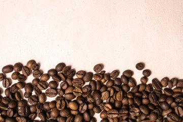 Roasted coffee beans in bulk on a light pink background. dark cofee roasted grain flavor aroma cafe, natural coffe shop background, top view from above, copy space