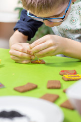 Dziecko w kuchni. Dekorowanie ciastek kolorowym lukrem. Ręce dziecka wyciskają lukier w kolorze żółtym. © Tomasz