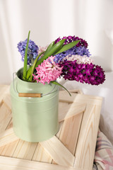 Beautiful hyacinths in metal can on wooden crate indoors. Spring flowers